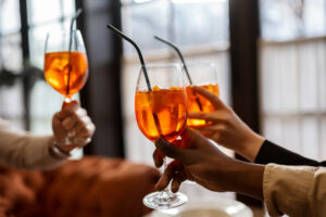 Nell'immagine tre persone che brindano con alcuni cocktail