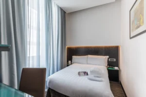 Nell'immagine la camera con letto matrimoniale e ai lati due comodini. Di fronte al letto una scrivania con una sedia.